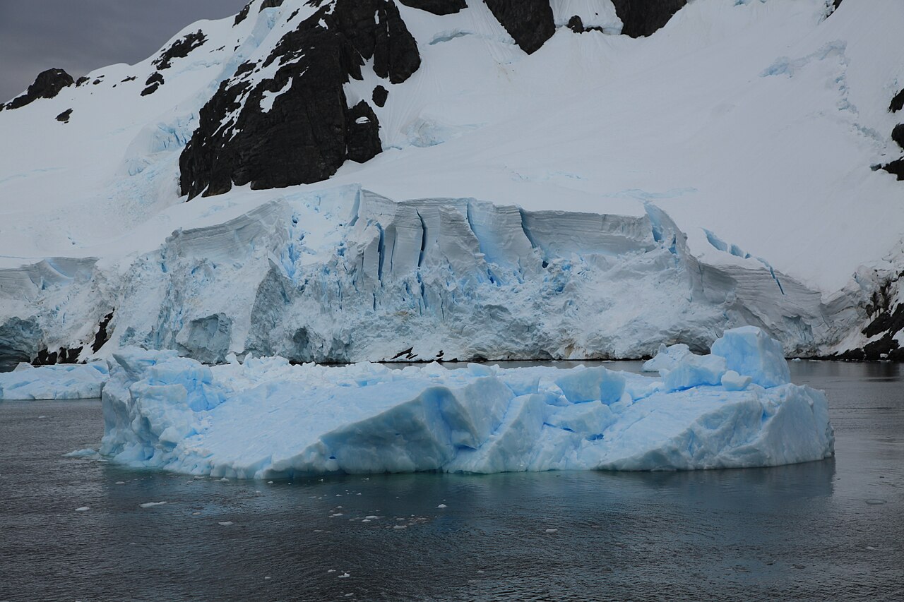 Tabular iceberg and glacier face reflected in calm water in the Lemaire Channel, Antarctic Peninsula